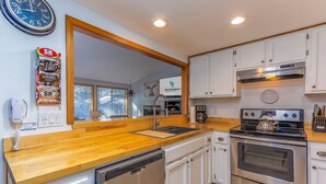 A modern kitchen with white cabinets, stainless steel appliances, and a wooden countertop. - AWBR04 - Walk to Fort Rock, Single Level, Hot Tub, Bikes, BBQ (Sunriver)