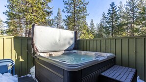 A hot tub with a wooden deck and a wooden fence, surrounded by trees. - AWBR04 - Walk to Fort Rock, Single Level, Hot Tub, Bikes, BBQ (Sunriver)