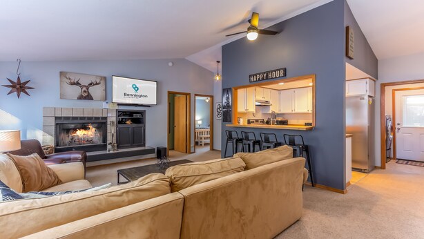 A modern living room with a fireplace, a sofa, a dining area, and a kitchen. - AWBR04 - Walk to Fort Rock, Single Level, Hot Tub, Bikes, BBQ (Sunriver)