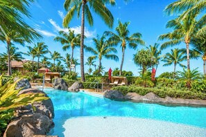 A resort pool with palm trees, lounge chairs, and a clear blue sky. - Honua Kai | Ocean View 2 BR Sleeps 6 | Car Incl. w/ 6+ Nights | HKK-334 by KBM (Lahaina)