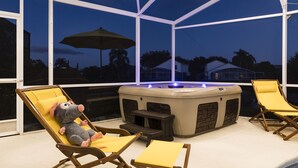 An outdoor hot tub area with lounge chairs and a plush toy. - Remy's Refuge: Stylish & Fun 4BR Retreat with lake view. 10 mins to Disney! (Kissimmee)
