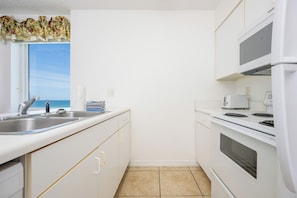 Una cocina funcional con ventana, microondas, horno y lavamanos.