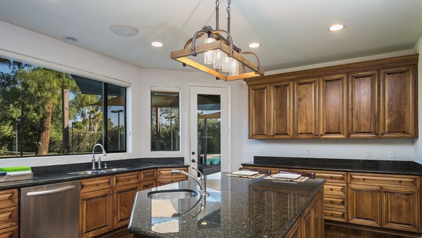 A modern kitchen with wooden cabinets, granite countertops, and a stainless steel dishwasher. - PRIVATE TENNIS + SEPARATE PICKLE COURT, HUGE HEAT POOL, SHUFFLEBOARD, PUTT GOLF! (Scottsdale)