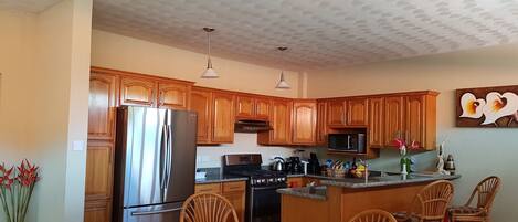 A modern kitchen with wooden cabinets, stainless steel appliances, and a central island with seating.