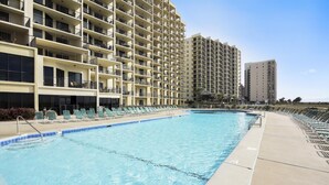 A swimming pool with lounge chairs and a high-rise building in the background. - Phoenix VII 301 | Beachfront | Updated | Pools | My Beach Getaways (Orange Beach)