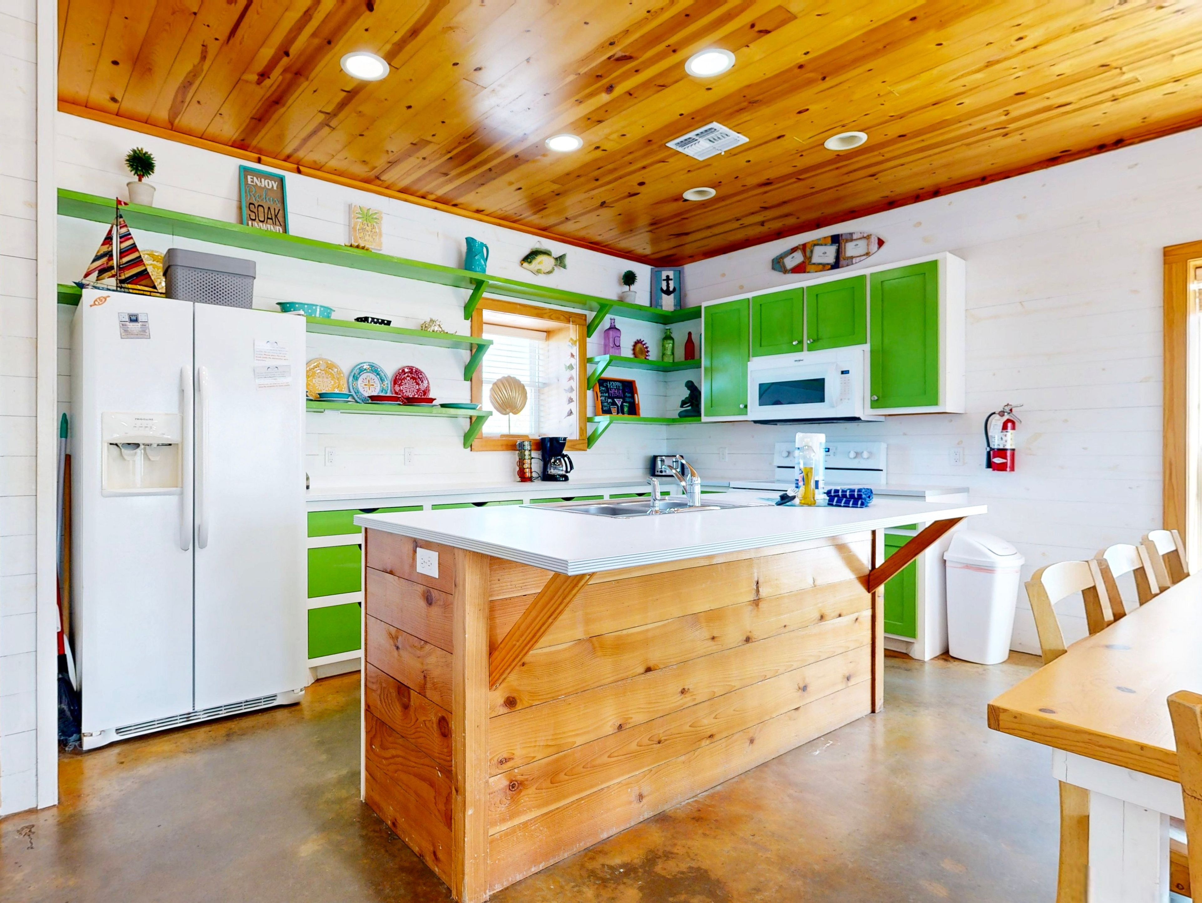 Une cuisine avec des meubles en bois, un îlot central et un réfrigérateur.