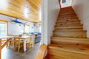 A wooden staircase leading to an upper level, a dining area with a table and chairs, and a blue fish decoration on the ceiling.