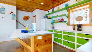 Eine Küche mit Holzschränken, einer weißen Arbeitsplatte und einer grünen Spritzschutzwand.