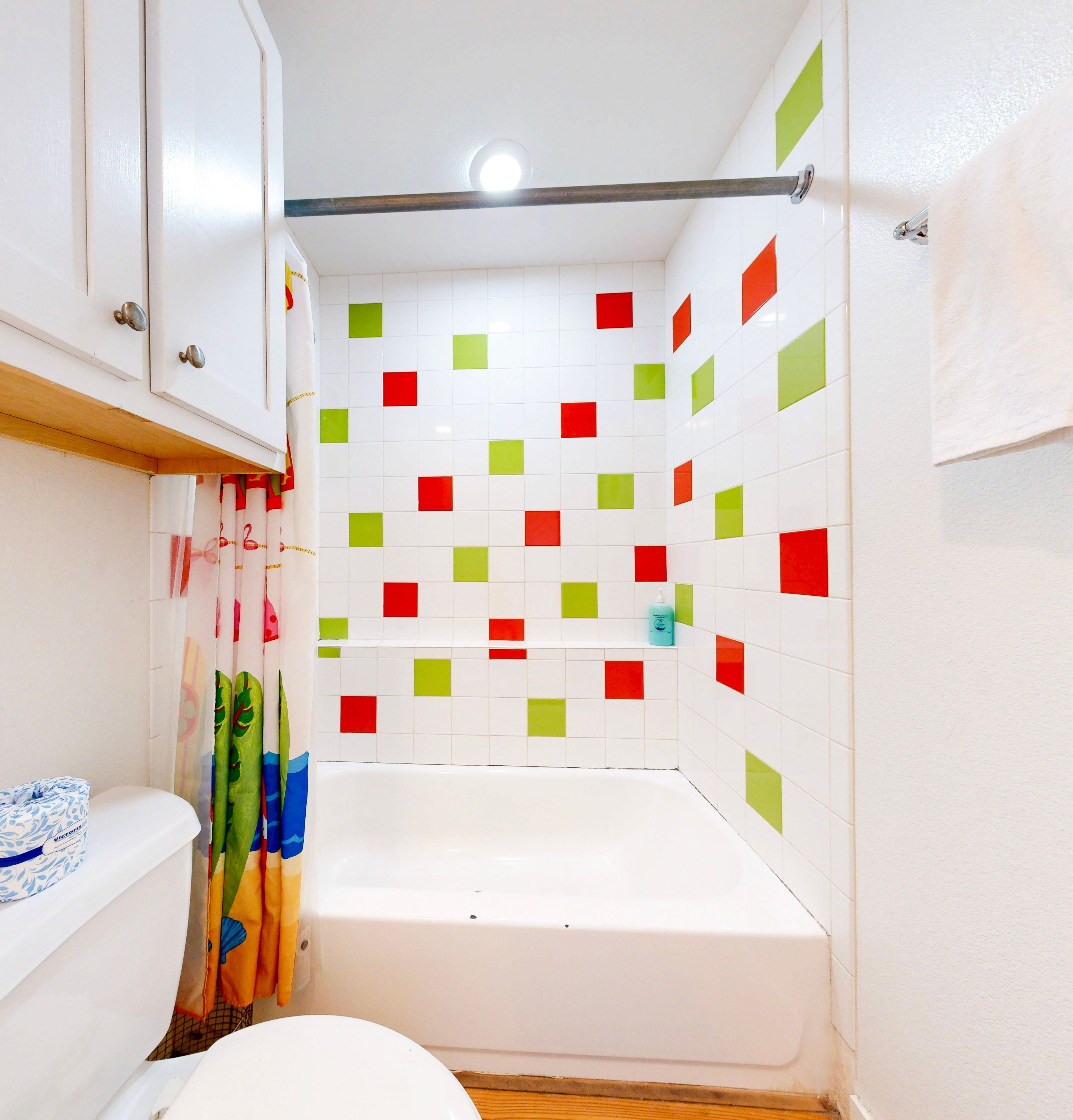 A bathroom with a bathtub, a toilet, and a shower curtain.