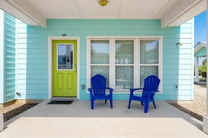 A house with a green door, two blue chairs, and a number '103' on the wall.
