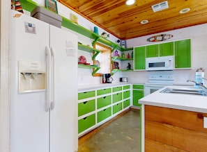 A kitchen with green cabinets, a white refrigerator, a microwave, and a sink. - Pet Friendly, Close to beach, Shared Pool, Golf Cart Access (Port Aransas)