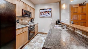 A kitchen with wooden cabinets, a granite countertop, a stainless steel sink, and a microwave. - Tl2210 Perfect for A Couple! Winter Specials!! Many Outdoor Activities! (Steamboat Springs)