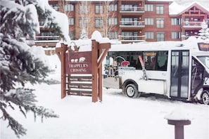 A snow-covered bus with a sign indicating 'Trappeur's Crossing' and a list of lodge names.