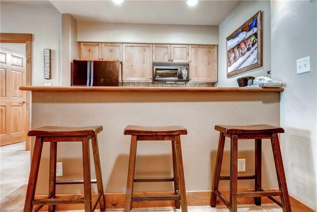 A kitchen with wooden cabinets, a microwave, and a wooden countertop. There are three wooden stools.