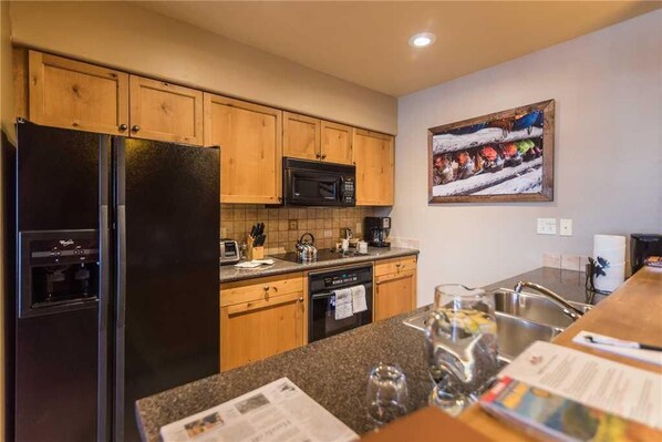A kitchen with wooden cabinets, a black refrigerator, a microwave, and a coffee maker. - Tl2210 Perfect for A Couple! Winter Specials!! Many Outdoor Activities! (Steamboat Springs)