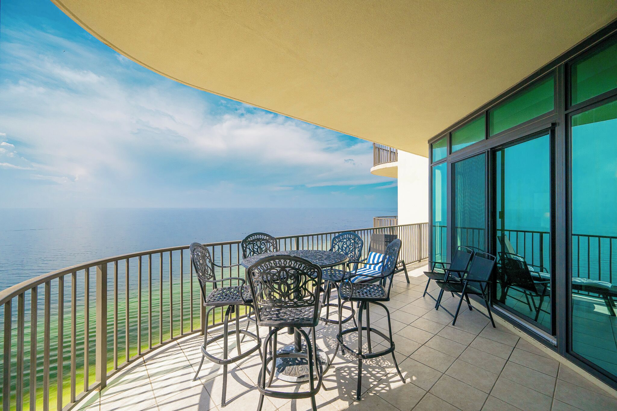 Ein Balkon mit Tisch und Stühlen mit Blick auf ein Gewässer.