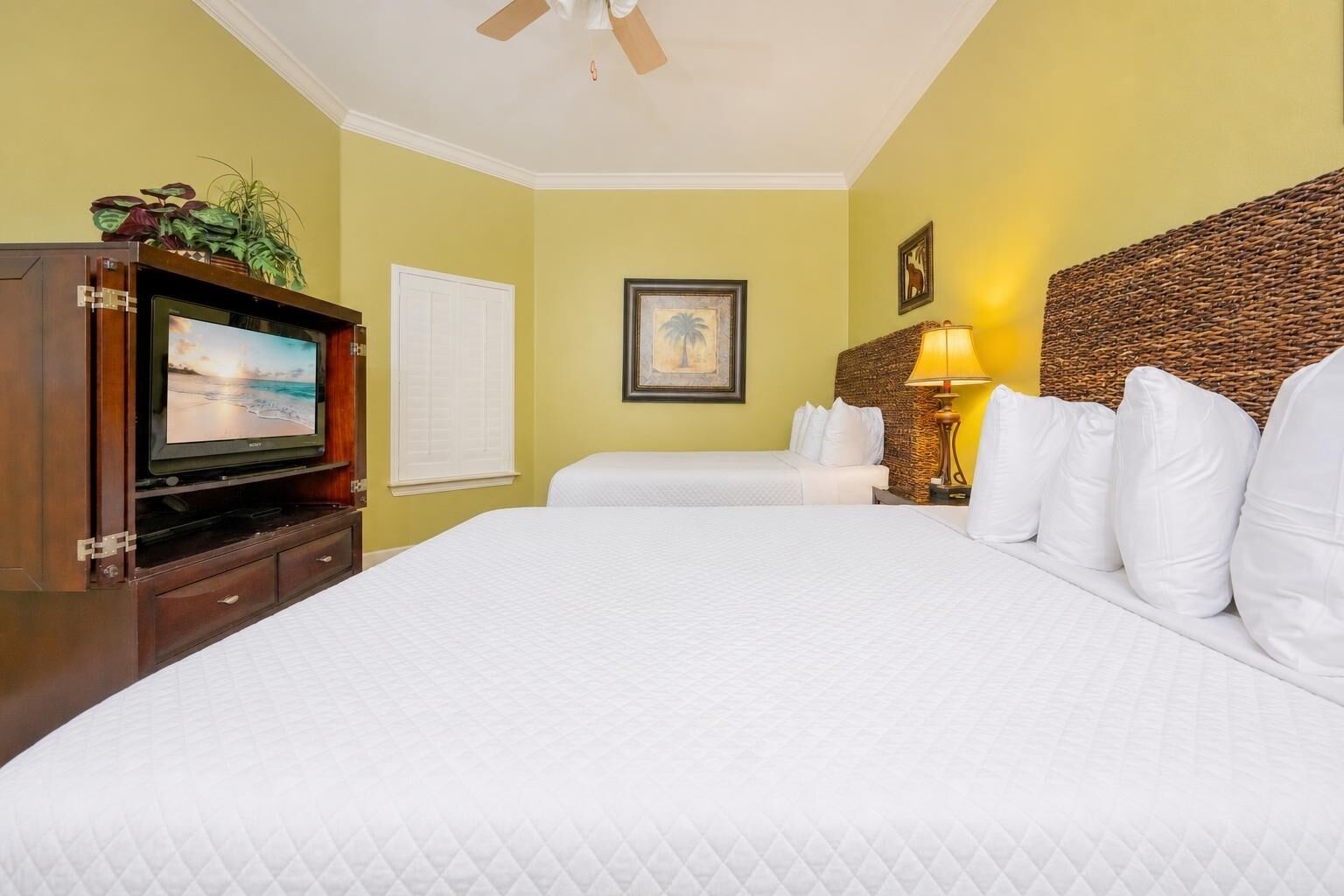 A hotel room with a bed, a television, a lamp, and a painting on the wall.