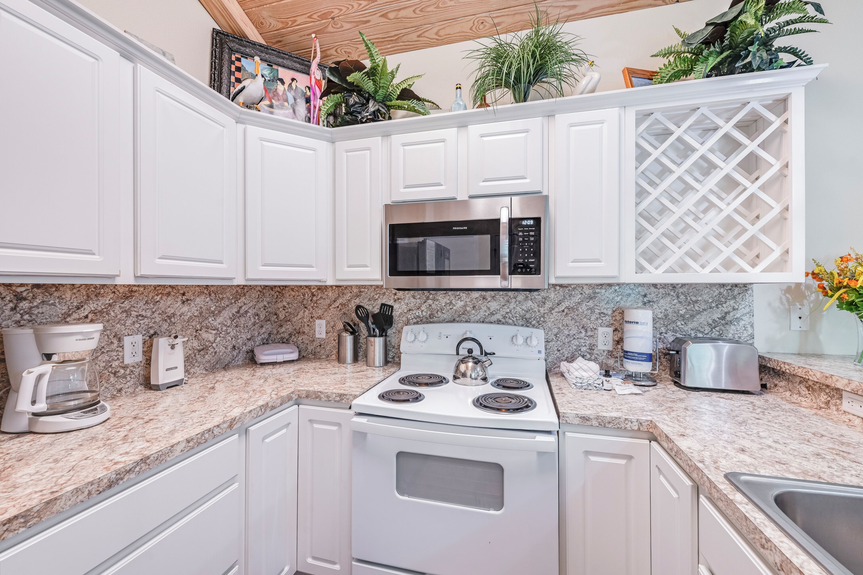 A kitchen with white cabinets, a stainless steel microwave, a stove, and a granite countertop.