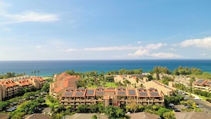 A resort with multiple buildings, solar panels on rooftops, and a view of the ocean.