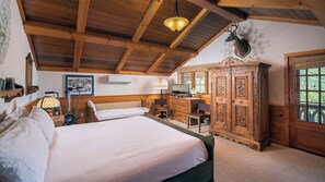 Una habitación de madera con una cama, un escritorio, un televisor y un armario.
