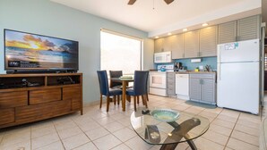 Una cocina compacta con comedor, televisión y mesa de vidrio.