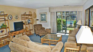 Una sala de estar con sofá, sillones, una mesa de centro, televisor y estantería.