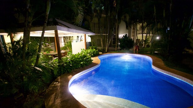A swimming pool surrounded by lush greenery and a covered seating area. - All About Location! Perfect, Well Equipped Condo 300 Yards From Beach, 2 Pools (Tamarindo)
