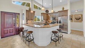A spacious kitchen with a large island, bar stools, and modern appliances.