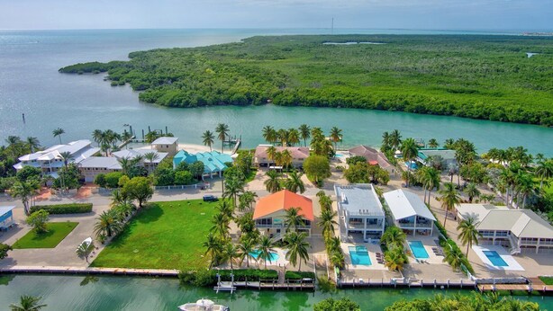 A coastal resort with multiple buildings, a marina, and a large body of water.