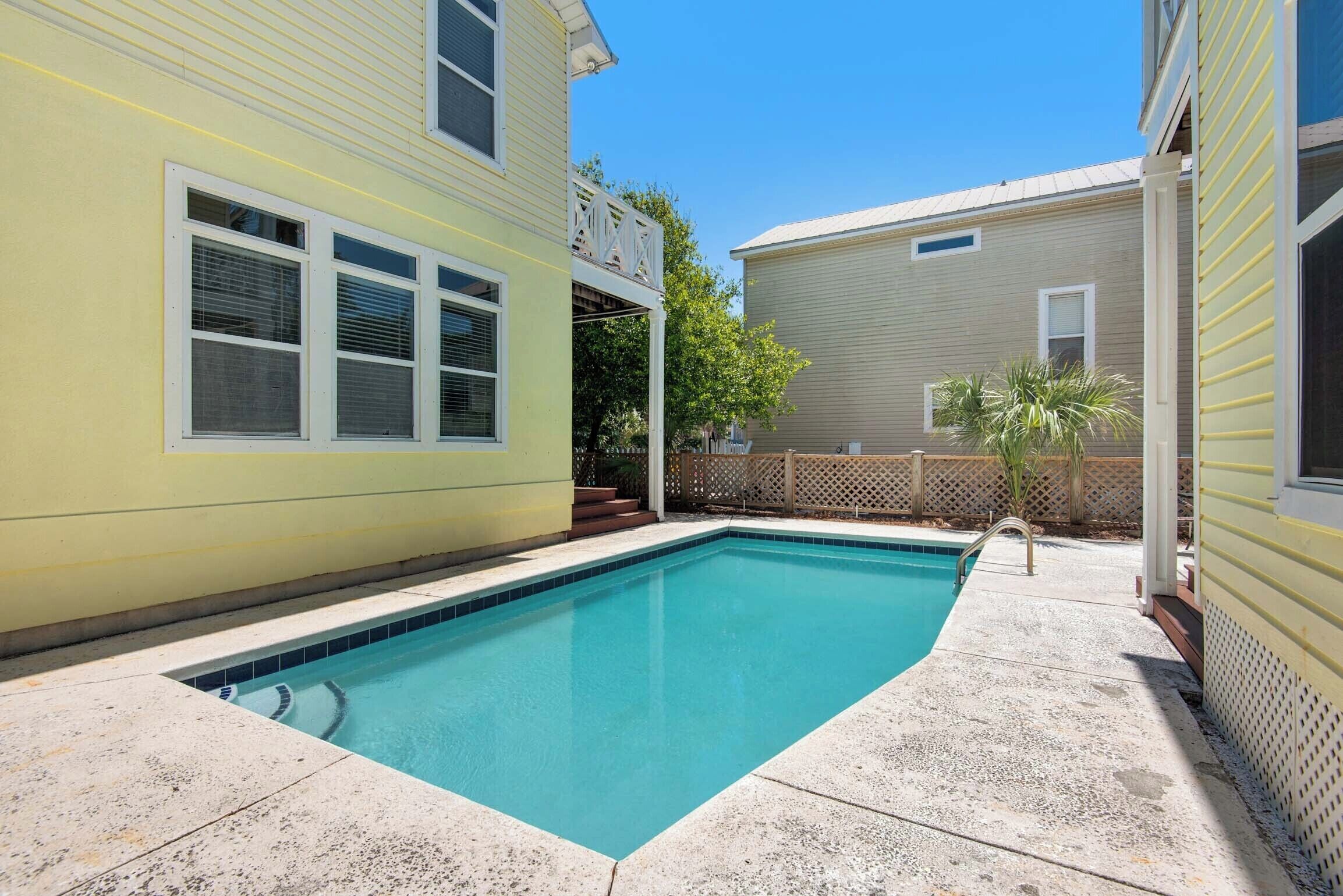 A rectangular swimming pool with a tiled edge, surrounded by a concrete deck.