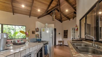 Cocina con estufa a gas, horno, refrigerador y un ventanal grande.