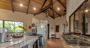 Une cuisine équipée d’une cuisinière à gaz, d’un four, d’un réfrigérateur et d’une grande fenêtre.