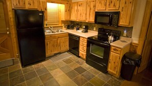 Una cocina compacta con armarios de madera, un refrigerador negro, un microondas, una estufa y un lavaplatos.