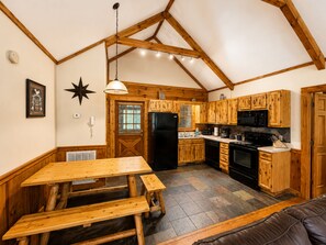 A kitchen with wooden cabinets, a black refrigerator, and a stove.