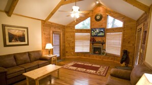 Un salón acogedor con techo de madera, chimenea, televisor y un sofá cómodo.