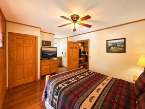 A bedroom with a bed, a ceiling fan, wooden doors, a television, and a kitchen area. - ER79 - Robyn's Nest - Great location. Close to all the action! (Pigeon Forge)