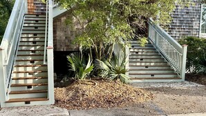 Una casa de dos pisos con un tejado pronunciado, un porche delantero y una escalera que conduce a la entrada.