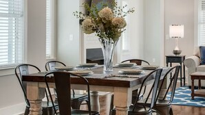 Een eetkamer met een houten tafel, zes stoelen, een bloemenvaas en een hanglamp.