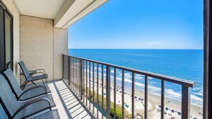 A balcony with a view of the beach and ocean.