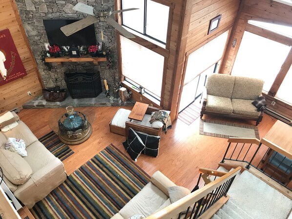 A cozy living room with a stone fireplace, wooden beams, a sofa, a chair, and a staircase. - 7 SPRINGS RESORT! Stay 3 nts get 1 nt free! You’ll love it here! 3bd-3ba loft. (Champion)