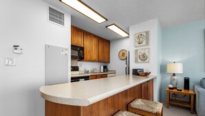 A kitchen with wooden cabinets, a built-in island, and a dining area with two chairs.