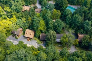 An aerial view of a residential area with multiple houses, a swimming pool, and a well-maintained lawn.