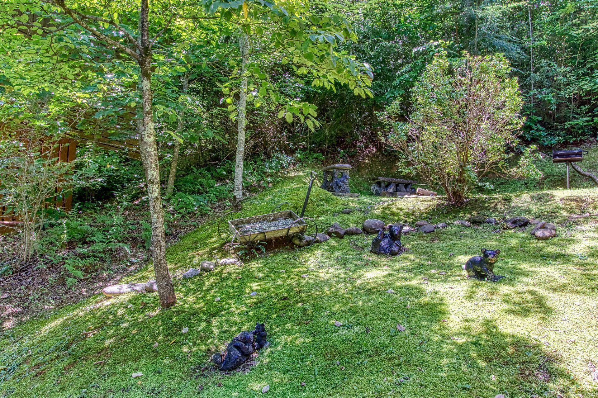 Un jardin agrémenté de statues en pierre, d’un banc en bois et d’un sentier dallé.