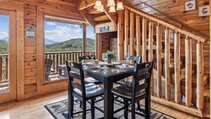 Eine Holzhütte mit Essbereich, einer Treppe und Blick auf die Berge.