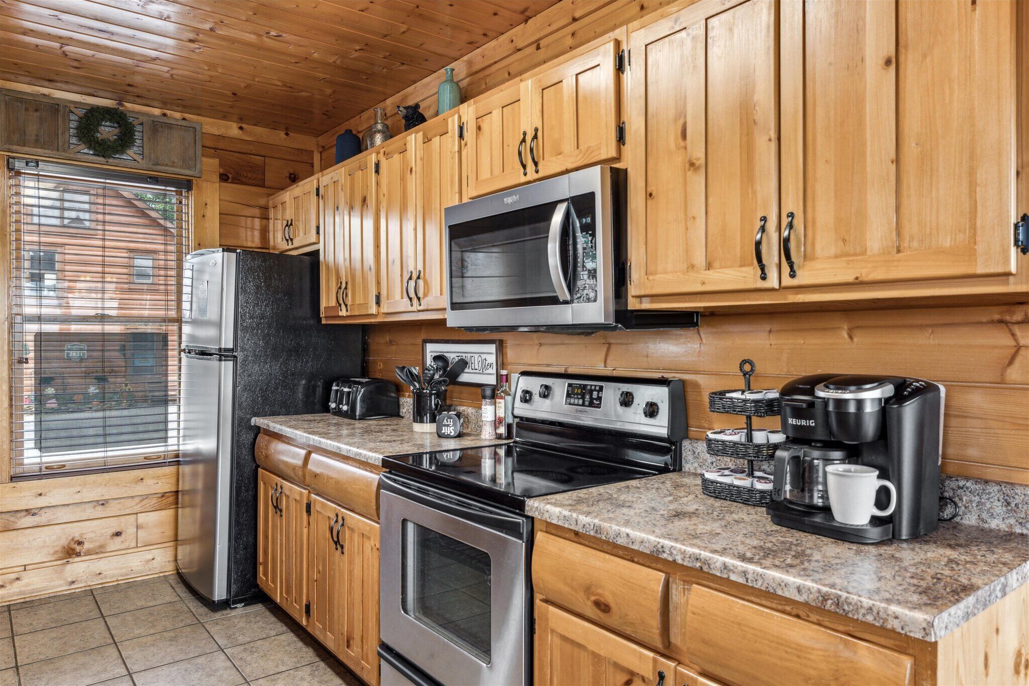 A kitchen with wooden cabinets, a stainless steel refrigerator, a microwave, an oven, and a coffee maker.