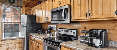 A kitchen with wooden cabinets, a stainless steel refrigerator, a microwave, an oven, and a coffee maker.