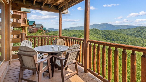 Eine Holzterrasse mit Tisch und Stühlen, mit Blick auf eine Berglandschaft.