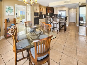 A spacious kitchen with a large island, wooden chairs, and a dining table.