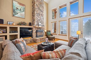 Cozy living room with a fireplace, comfortable seating, and a TV, offering a view of the outdoors.