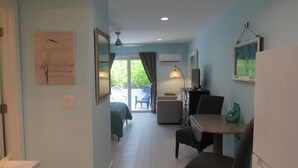 Habitación de hotel con cama, escritorio, silla, televisor y ventana con cortinas.